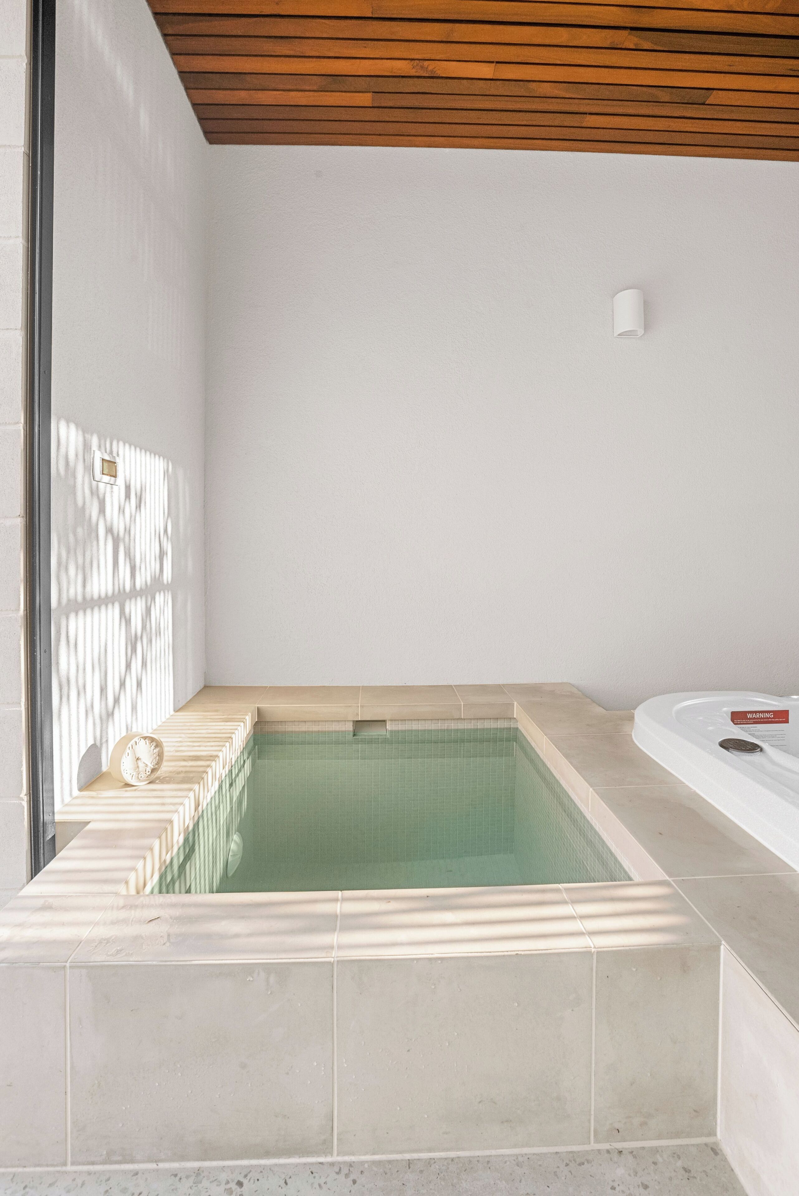 A modern bathroom with a rectangular bathtub, a separate shower area, and a small seating bench.