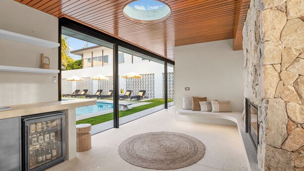 Ein modernes Interieur mit Blick auf einen Pool, einer integrierten Minibar und einer Wand mit Steinverkleidung.