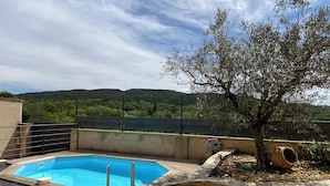 A swimming pool with a stone border and steps leading into it, surrounded by a stone wall and a fence. - House with swimming pool in Vaison-la-Romaine, Provence (Vaison-la-Romaine)