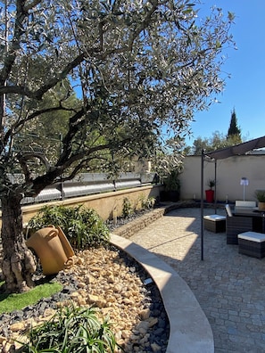 An outdoor patio area with a stone pathway, seating, and a tree.