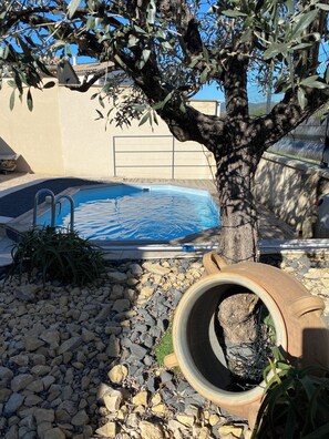 A swimming pool surrounded by rocks and a tree.
