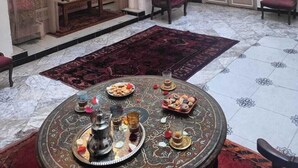 A traditional Moroccan interior with a seating area, a dining table with a tray of pastries, and two hanging lanterns. - Dar Le Monde (Marrakech)