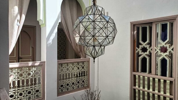 A traditional interior with geometric patterned windows and a hanging light fixture. - Dar Le Monde (Marrakech)