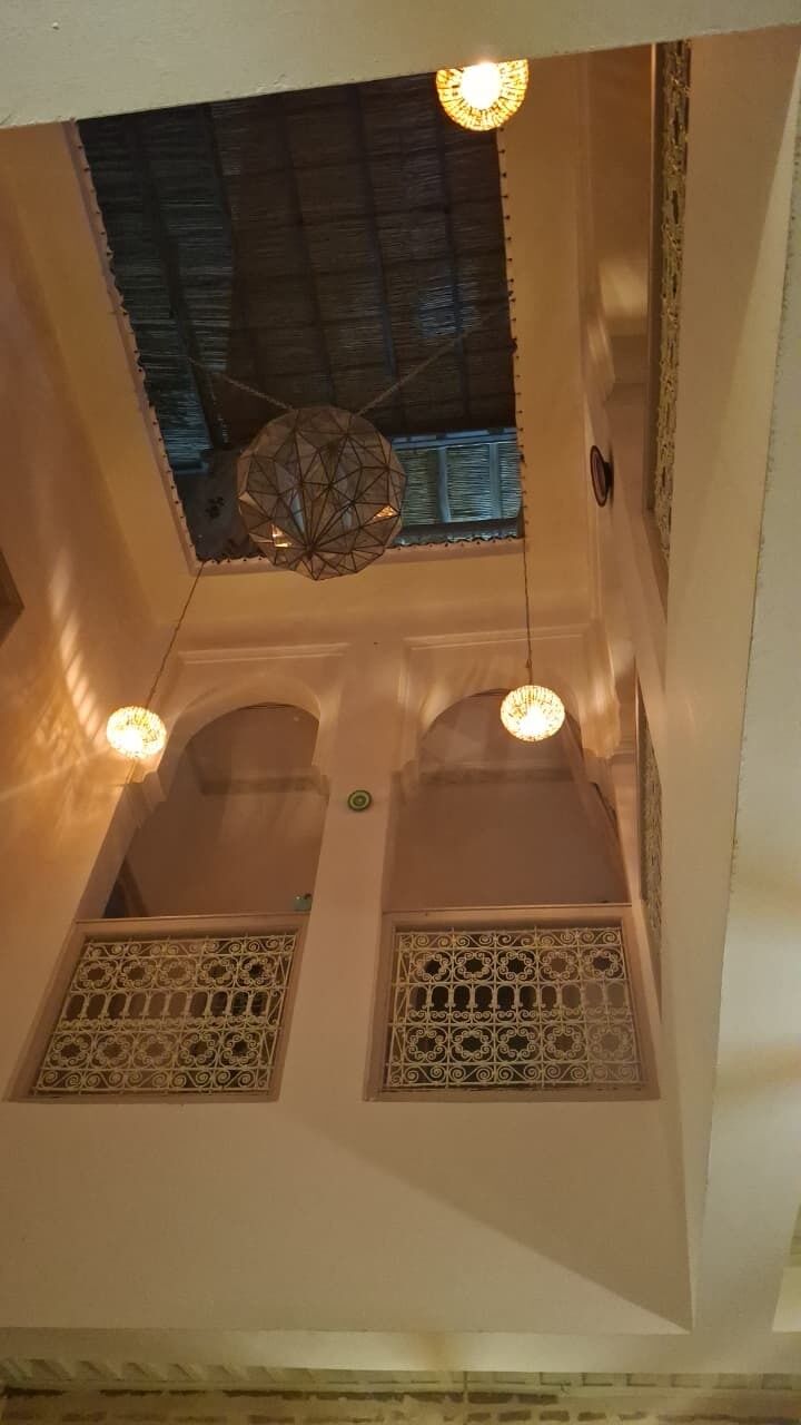 A room with a high ceiling, decorative ceiling fan, and two windows with intricate lattice designs.