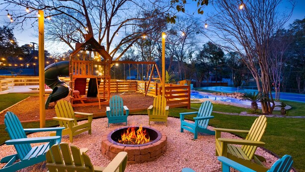 A playground with a swing set and a fire pit surrounded by Adirondack chairs. - Pickleball & Heated Pool & Game Room & Mini Golf (San Antonio)