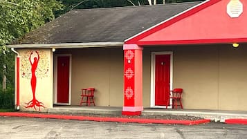 A building with a red exterior, two red doors, and a small porch area with two red chairs.