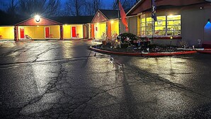 Ein Motel mit großem Parkplatz und einem begrünten Innenbereich mit Kübelpflanzen.