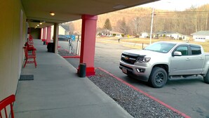 Ein Parkplatz mit einem weißen Pickup, roten Stühlen und einem überdachten Gang.