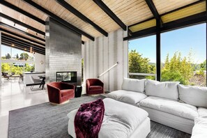 A modern living room with a fireplace, white sofa, and red armchairs. - Refreshed Mid-Century Retreat | Private Heated Pool, Spa, Steam & City Views (Los Angeles)