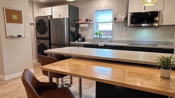 A modern kitchen with a central island, stainless steel appliances, and pendant lighting. - DWELL in Alaska "BIGGER" Unit k (Fairbanks)