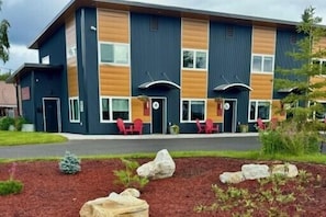 A modern building with a two-story structure, large windows, and a landscaped front yard with rocks and plants.