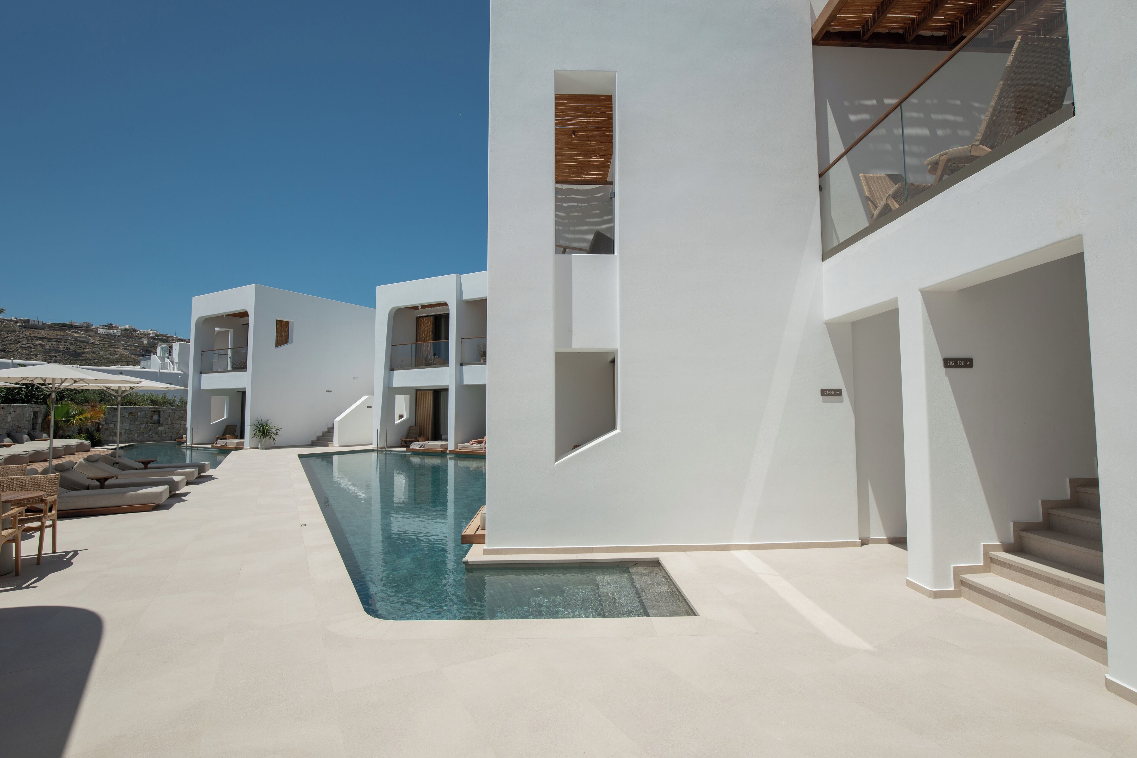 A modern building with a swimming pool, outdoor seating, and a staircase.