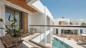 Een modern buitenzwembad met een glazen balustrade, lounge fauteuils en een eethoek.