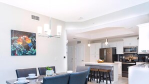 Une cuisine moderne avec des meubles blancs, un réfrigérateur noir et un four à micro-ondes.
