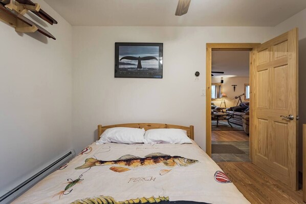 A bedroom with a bed, a wooden headboard, a wall-mounted picture, and a wooden door. - Catskill Creekside Retreat (Hamden)