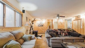 Un salon confortable avec un canapé, un divan et une table basse. Un trépied et un appareil photo sont posés sur le sol.