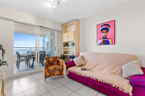 Een woonkamer met een bank, fauteuil en een eethoek met stoelen en een tafel.