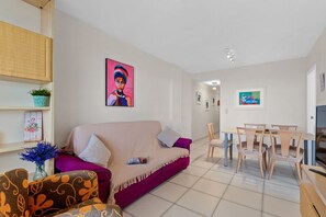 Een woonkamer met een bank, een eettafel met stoelen en een televisie.