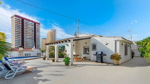 Um imóvel residencial com um pátio, área de estar externa, churrasqueira e piscina.
