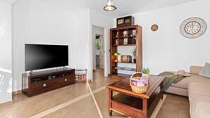 Uma sala de estar com televisão de tela plana, móvel de entretenimento de madeira e uma estante de livros.