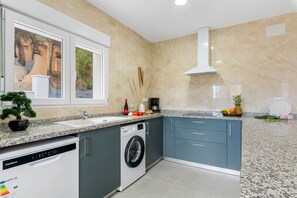 A modern kitchen with a built-in washer, a window with a view, and a countertop with various items.