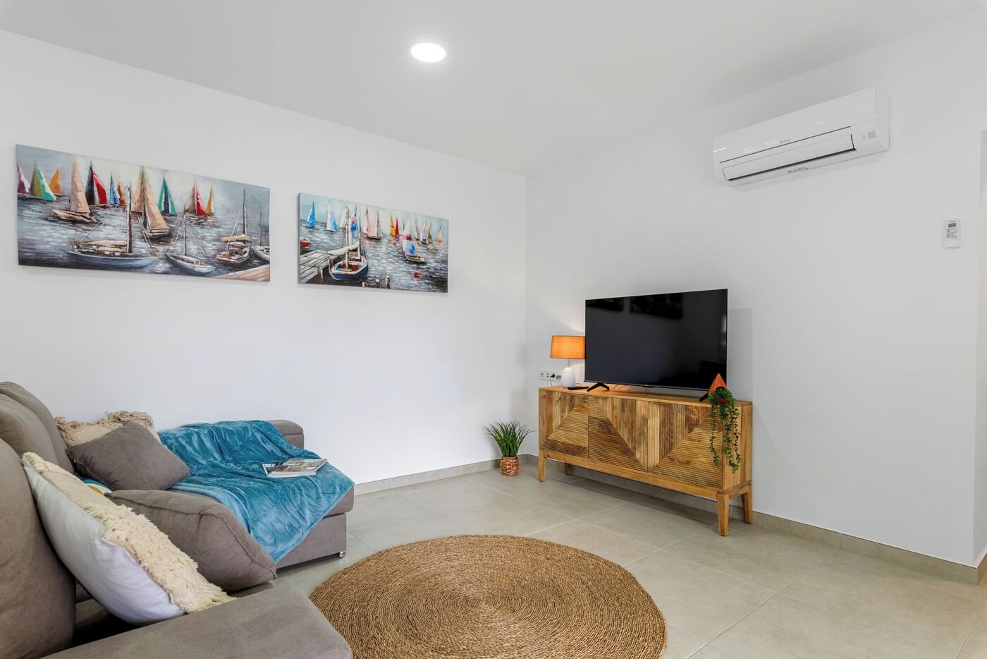 Un soggiorno con un divano, una televisione su un mobile in legno e due quadri appesi al muro.