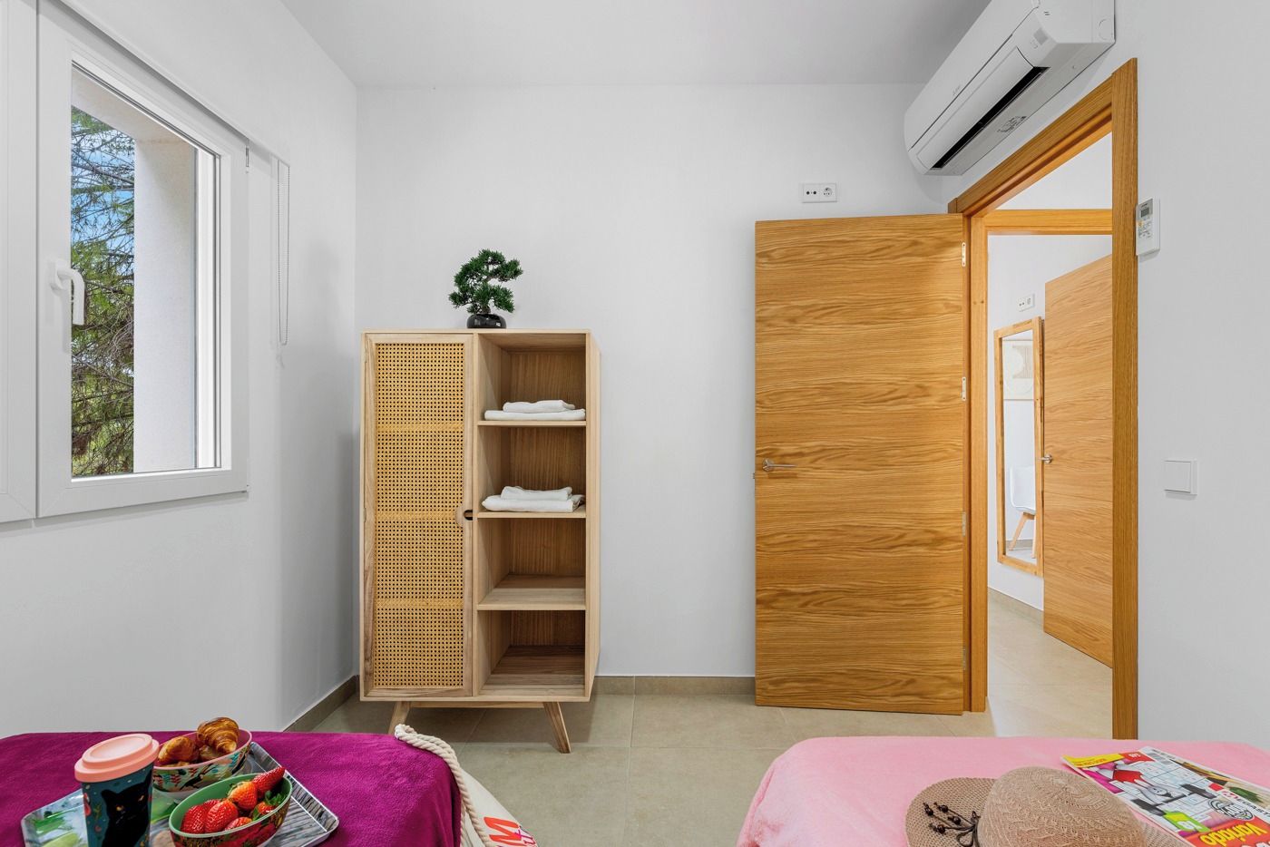 Une pièce comprenant une armoire en bois, un lit, une fenêtre et un appareil de climatisation.
