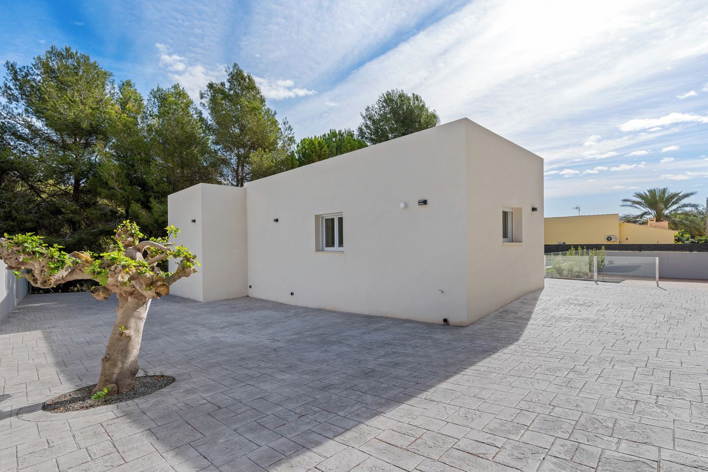 Un bâtiment moderne doté d’un toit plat et d’une cour dallée.
