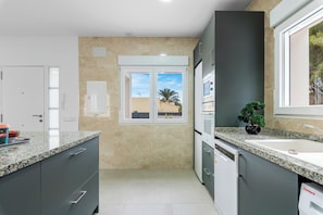 A modern kitchen with granite countertops, a double sink, and a view through the window.