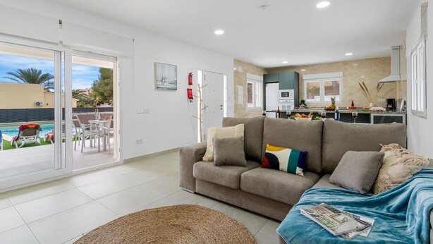 Uma sala de estar moderna com um sofá cinza, uma mesa de centro e vista para uma piscina.