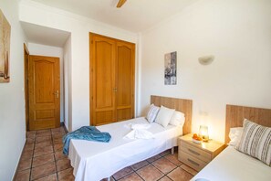 A hotel room with a bed, bedside table, and a nightstand with a lamp.