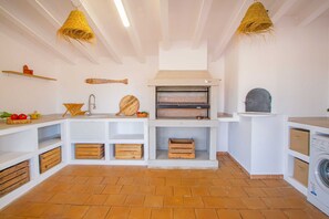 A kitchen with a built-in oven, wooden storage, and hanging light fixtures.