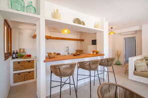 Een moderne keuken met een houten aanrecht, barstoelen en een hangende lamp.