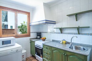 Een kleine keuken met een magnetron, fornuis en wastafel.