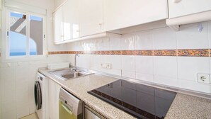 A kitchen with white cabinets, a double sink, a Bosch dishwasher, and a patterned backsplash. - Apartamento Lynapic - Plusholidays (Calpe)