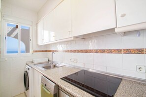 Uma cozinha com armários brancos, pia dupla, lava-louças Bosch e painel de fundo estampado.