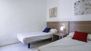 A hotel room with two beds, a nightstand, a wall-mounted lamp, and two pieces of wall art. - Apartamento Lynapic - Plusholidays (Calpe)