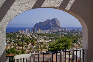 A cityscape with a prominent mountain in the background, a clear sky, and a view through an archway. - Apartamento Lynapic - Plusholidays (Calpe)