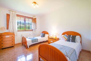 A bedroom with two beds, a dresser, a window with curtains, and a ceiling light.