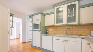 Una cocina con gabinetes blancos, lavavajillas y salpicadero de azulejos.