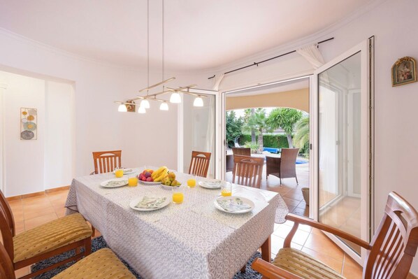 A dining area with a table set for four, chairs, and a view of the outdoors through a glass door.