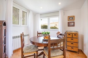 A dining area with a round table, chairs, a basket of bread, and a radiator.