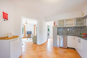 A modern kitchen with white cabinets, a tiled backsplash, and a dishwasher.