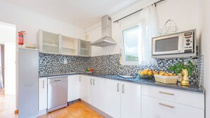 Cocina moderna con armarios blancos, lavavajillas de acero inoxidable, microondas y salpicadero de azulejos.