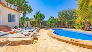 Un área de piscina con sillas de descanso, piscina y palmeras.