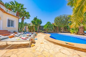 A pool area with lounge chairs, a swimming pool, and palm trees. - Villa Duke - Plusholidays (Calpe)