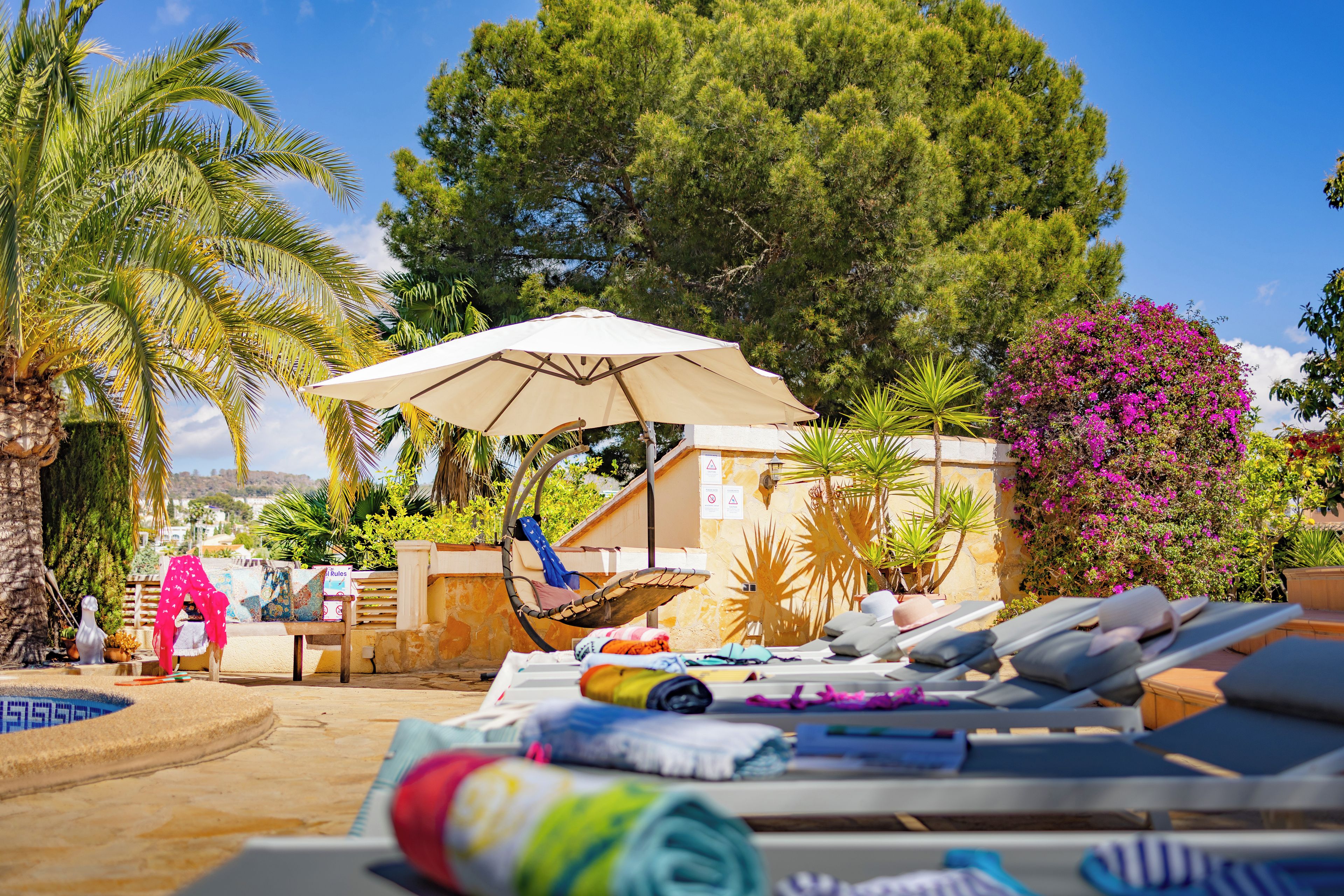 A poolside area with lounge chairs, an umbrella, and a hammock.