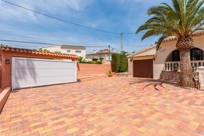 A residential property with a paved driveway, a garage, and a palm tree.
