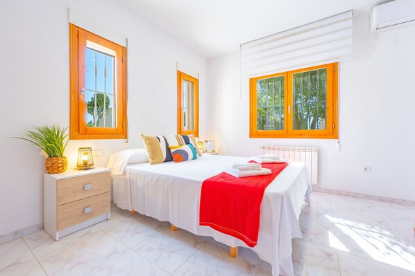 A bedroom with a bed, bedside tables, and windows.