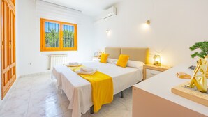 Habitación de hotel con una cama grande, un escritorio, una silla, un ventanal con vistas a la vegetación y una mesita con una lámpara.
